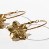 Aros tipo argolla dorados con dije de flor calada.