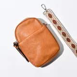 Porta celular marrón de cuero sintético con correa de tela estampada.