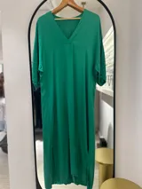Túnica o vestido largo de manga corta, color verde esmeralda, con escote en V y corte holgado tipo caftán. Presenta aberturas laterales en el bajo.
