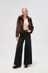 Chaqueta corta negra de piel sintética con cuello clásico, cierre frontal con cremallera y mangas largas.