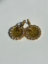 Aros colgantes dorados con dije circular de resina con glitter dorado y borde de strass blancos.