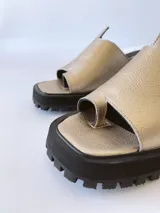 Sandalias doradas con tira para el dedo y suela track negra.