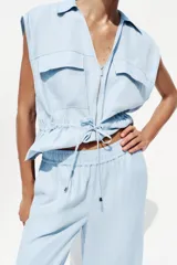 Pantalón celeste de tiro alto con cintura elástica, bolsillos delanteros y pernera ancha.