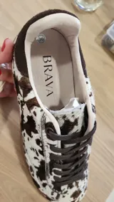 Zapatillas urbanas con estampado animal print en blanco y negro, detalles en gamuza negra y cordones negros. Incluye cordones crudos extra.