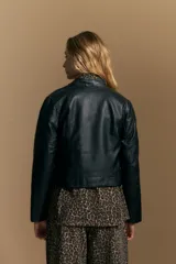 Campera negra de cuero sintético estilo biker, con cierre asimétrico, broches metálicos en el cuello y bolsillos con cierre.