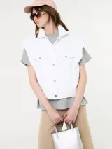 Chaleco blanco con detalle de desflecado en la sisa y botones metálicos.