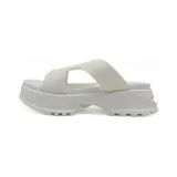 Sandalia blanca con plataforma gruesa y suela dentada. Presenta una faja ancha cruzada sobre el empeine.