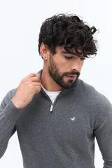 Sweater de tejido liso color verde oscuro, con cuello medio y cierre frontal parcial plateado. Presenta puños y cintura acanalados, y un pequeño logo bordado en el pecho.