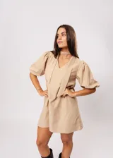 Vestido corto color beige, de corte oversize, con escote en V y mangas globo. Incluye cinturón marrón con hebilla dorada.