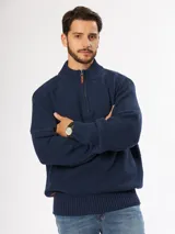 Sweater color verde oscuro, de punto grueso y diseño holgado, con cierre frontal y cuello alto.
