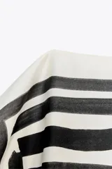 Top de Zara Woman Collection, con estampado abstracto en blanco y negro, cuello barco, mangas caídas y bajo ajustable con lazadas.