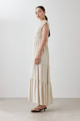 Maxi vestido color beige melange, con escote en V, mangas cortas y falda larga con volantes.