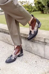 Botines de cuero negro con detalles en cuero marrón con textura de cocodrilo en la caña y cuero con estampado de piel de serpiente en el empeine. Cierre lateral con cremallera y tacón bajo. Estilo cowboy.