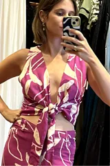 Top morado con estampado de flores blancas, escote en V y lazo en la cintura. Confeccionado en lino.