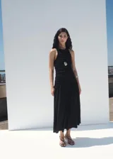 Vestido midi negro sin mangas, con cuello redondo, fruncidos laterales y diseño evasé.