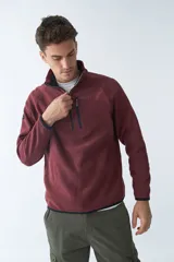 Buzo polar de algodón color bordó, con cuello elevado, medio cierre frontal, bolsillo con cierre en el pecho y logo estampado.