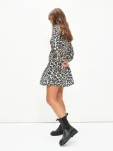 Vestido corto negro con cuello alto, mangas largas abullonadas y falda escalonada.