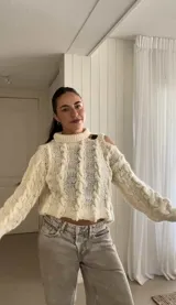 Sweater color crudo de lana merino con cuello alto y un solo hombro al descubierto, tejido a mano.