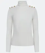 Blusa de tejido de punto acanalado color blanco, de manga larga y corte ajustado. Presenta cuello alto y detalles de botones dorados en los hombros.