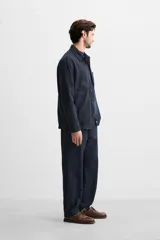 Pantalón azul marino de corte recto, confeccionado en tejido de algodón y lino. Tiene cintura elástica ajustable con cordón, bolsillos delanteros y traseros de vivo. Cierre frontal con cremallera y botón.