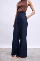 Pantalón ancho de tiro alto color azul marino, con pliegues frontales y ribetes en color naranja quemado en los bordes del bolsillo y la cintura.