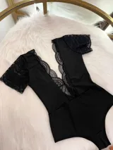 Body entallado de lycra negro con detalles en microtul y encaje, con escote pronunciado y collarín regulable desmontable.