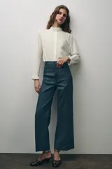 Camisa blanca de algodón con cuello con volantes y mangas largas con puños fruncidos.