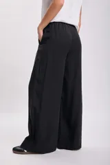 Pantalón negro de vestir de corte palazzo con cintura alta y lazo ajustable.
