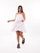 Vestido corto blanco con tirantes finos ajustables y falda escalonada con volados.