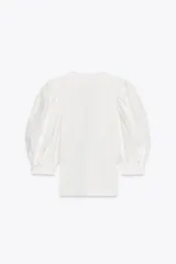 Top negro de escote pico con detalle de fornitura y mangas 3/4 abullonadas con estampado de flores bordadas.