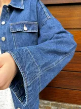 Campera denim azul con corte trench, bolsillos frontales y cierre con botones.