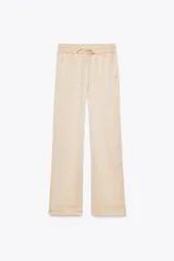 Pantalón de tiro alto color beige con cintura elástica ajustable con cordones, bolsillos delanteros y pernera ancha.