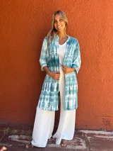 Camisa larga de manga tres cuartos, color verde azulado y blanco, con estampado tie-dye. Tiene cuello camisero, botones frontales y bolsillos en el pecho.