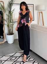 Musculosa negra con estampado floral en tonos rosa, naranja y marrón, con volados en el escote y ruedo. Cierre frontal con botones.