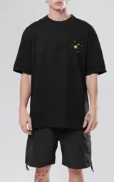 Remera negra de corte holgado con estampado en la espalda de un paisaje surrealista con planetas, lunas, escaleras y figuras geométricas.
