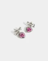 Aros colgantes cortos con pasante de moño plateado y dije de corazón con rosa roja en el centro y strass alrededor.