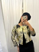 Chaqueta corta con mangas 3/4 y estampado abstracto en tonos beige, negro, gris y verde.