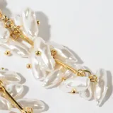 Aros colgantes dorados con perlas blancas irregulares.