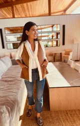 Chaleco marrón con interior de piel sintética color crema, sin mangas y con bolsillos laterales.