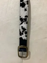 Cinturón con hebilla cuadrada de metal dorado y estampado animal en blanco y negro.