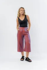 Pantalón capri de lino color borgoña con acabado metalizado tornasolado que refleja tonos entre rosa y lila. Tiene corte recto, ancho y fluido, con cintura elástica posterior.