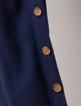 Pantalón blanco de algodón con pretina elastizada, bolsillos inclinados y ruedo lateral con tajo y botones.