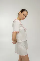 Blusa color naranja de lino manga corta con botones frontales y escote en V con detalle de bordado a contratono.