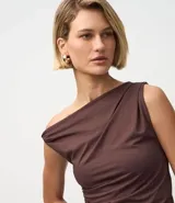 Blusa sin mangas color amarillo claro, confeccionada en microfibra, con escote asimétrico de un solo hombro, detalle torcido en el hombro y fruncidos en el cuerpo. Presenta un bajo asimétrico.