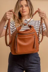 Cartera mochila color marrón de símil cuero suave con múltiples bolsillos con cierre, división al medio y correa ajustable de doble manija para llevar al hombro y como mochila.