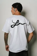 Remera blanca de algodón, corte regular fit, con un pequeño estampado ovalado en el pecho y un gran estampado de firma estilizada en la espalda.