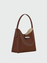 Bolso hobo Longchamp modelo Le Roseau M, color marrón cuero con cierre de broche metálico plateado y asa de hombro rígida negra.