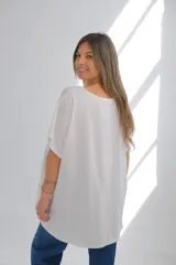 Blusa blanca de lino con cuello redondo, mangas cortas, bolsillo en el pecho y detalle de bordado calado en el lateral inferior. Corte holgado.