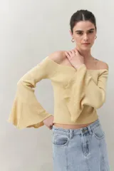 Top tejido color beige con escote off-shoulder y mangas largas acampanadas.