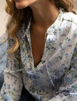 Blusa de gasa plisada estampada con flores azules, marca Floral & Ivy. Cuello a la base, escote en V y lazo de ajuste.